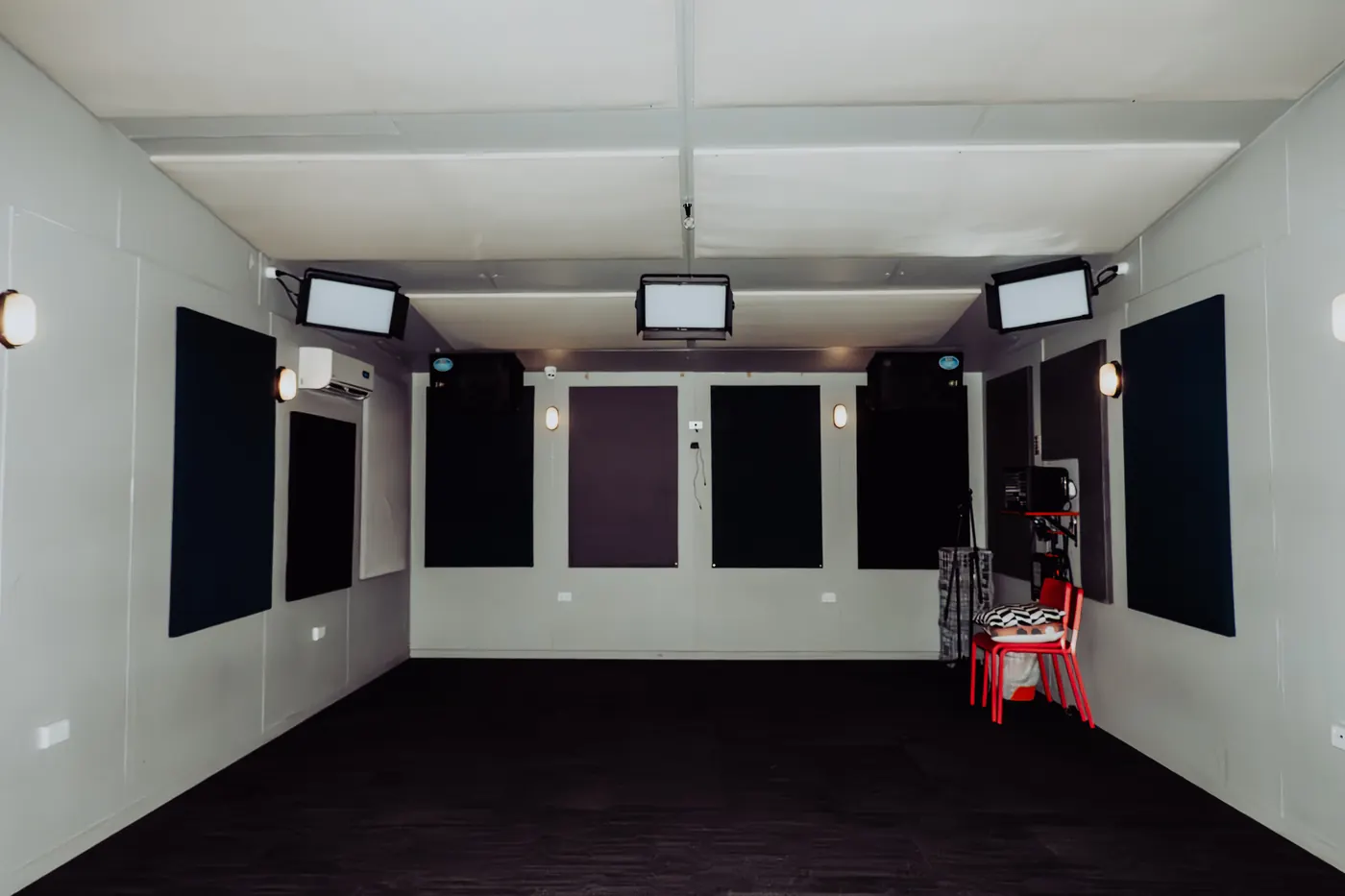 An empty rehearsal room with acoustic panelling and studio lighting
